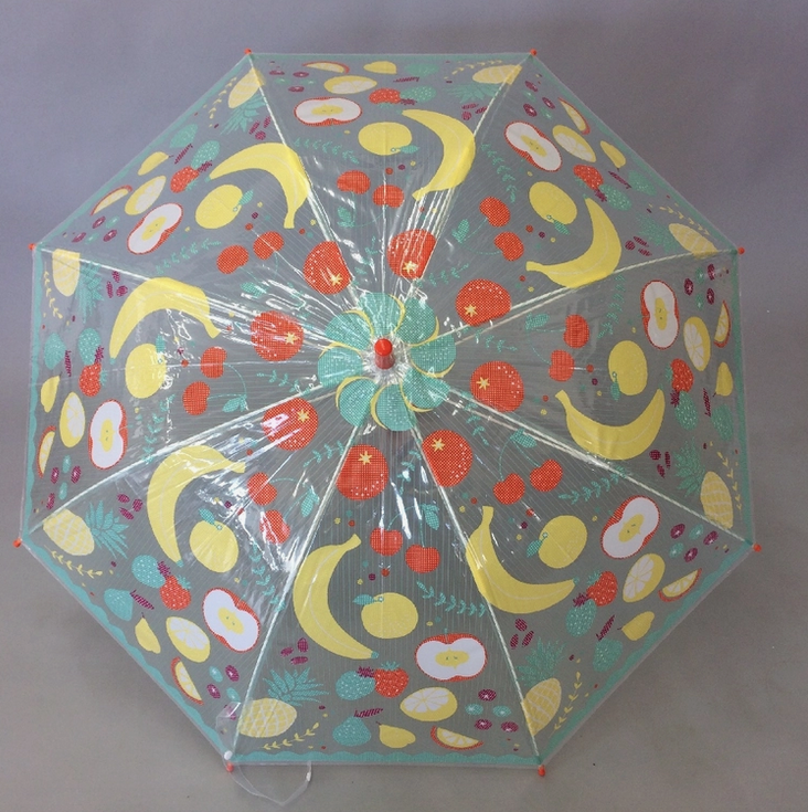 View from the top of the open clear vinyl umbrella with apples, bananas, oranges and other fruits printed all over it. 