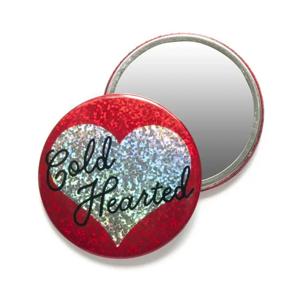 Round pocket mirror. Non-mirror side is red glitter with a silver glitter heart and reads Cold Hearted.