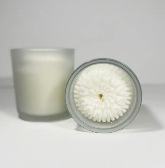 Two dandelion flower candles. One showing the top view and the other showing the glass candle holder. 
