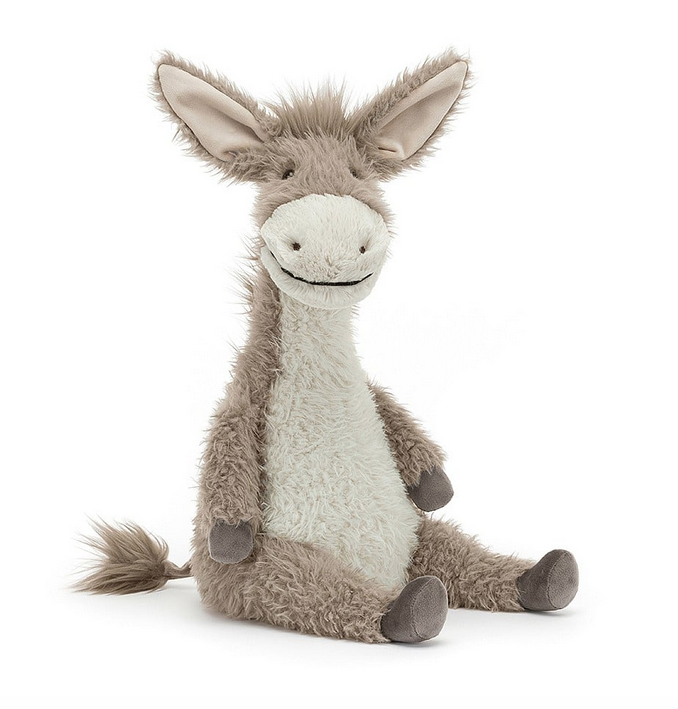Dario Donkey plush is sitting upright and facing forward with scruffy grey fur on his head, down his back and on his legs. His nose and belly are covered in white fur. 