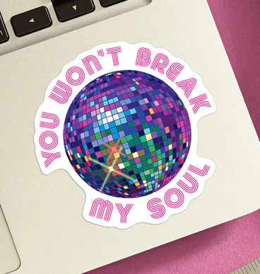 Die cut vinyl sticker with a shiny, multicolored disco ball, with the phrase "You won't break my soul" attched to the bottom corner of a laptop. 