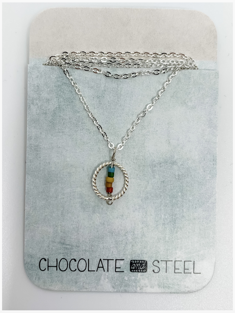Silver chain necklace with a twisted silver circle charm with a straight bar of rainbow colored beads from top to bottom.
