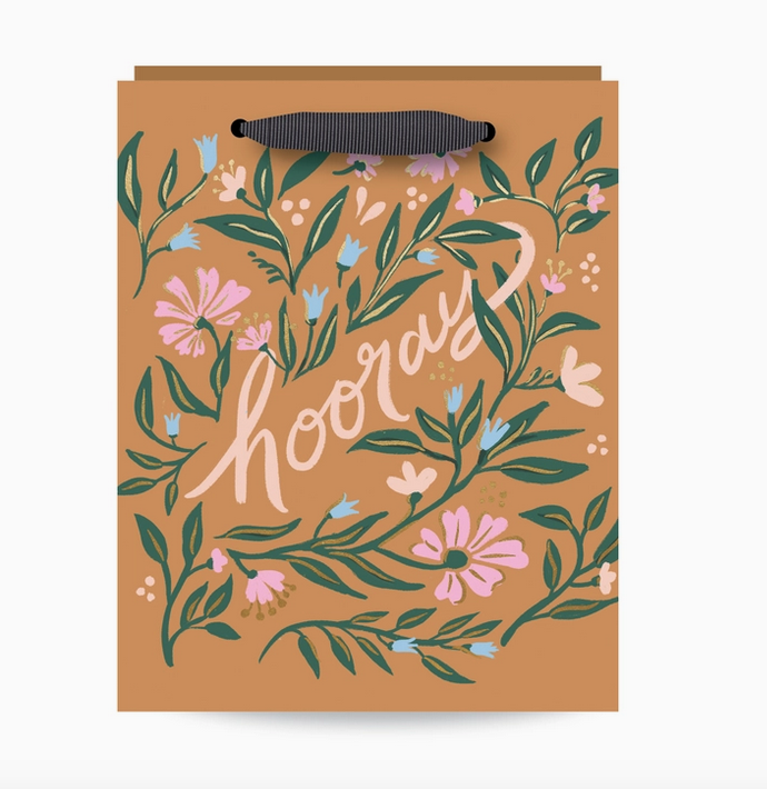 Gift bag with burnt orange background and floral pattern with green, blue, pink and purple flowers and gold foil accents. Lettering reads "hooray"