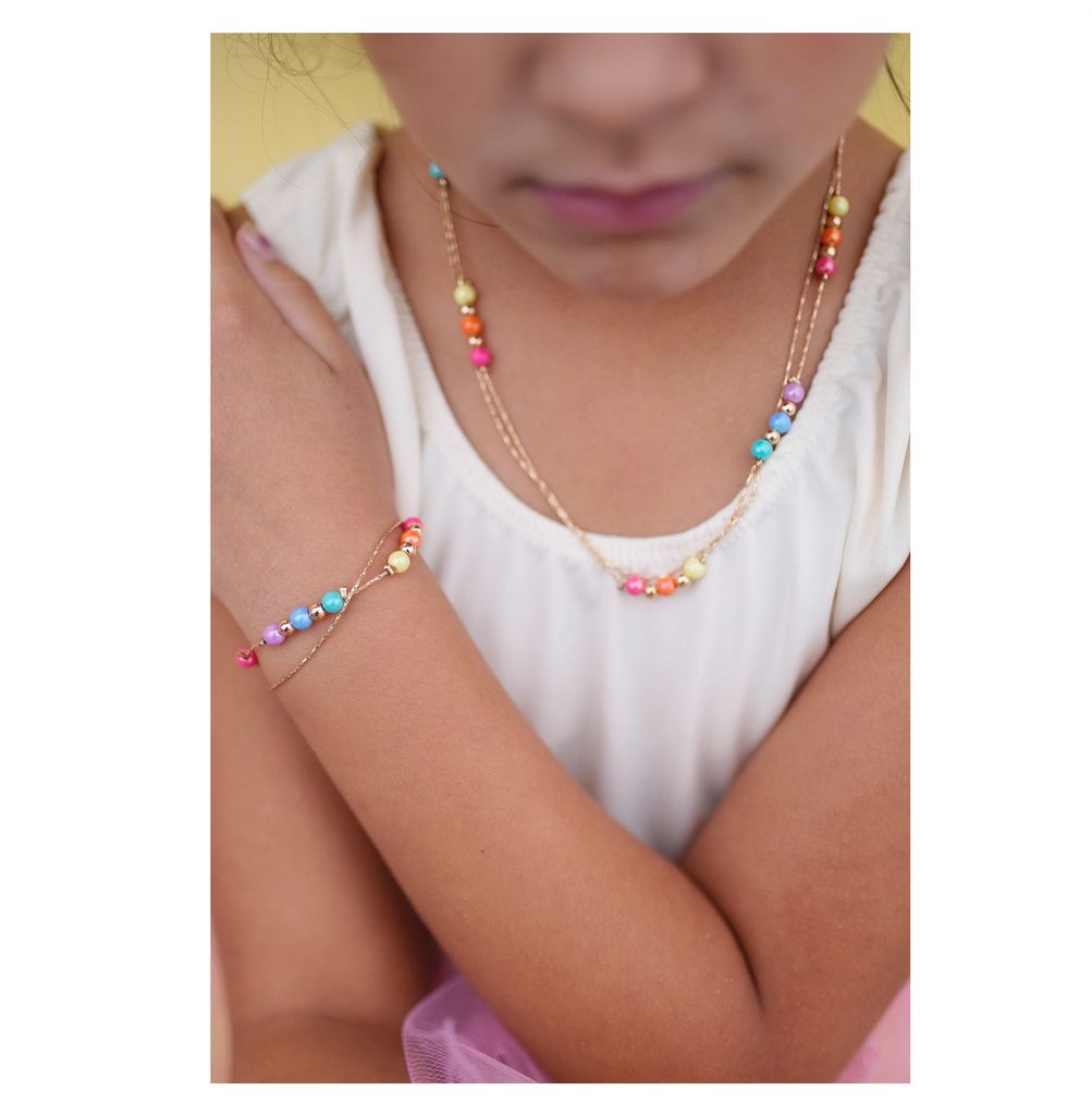 Child wearing golden rainbow necklace and matching bracelet.