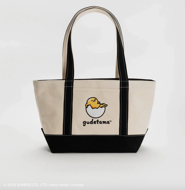 Canvas tote with navy trim and handles, with Gudetama relaxing in a cracked egg on the front. 