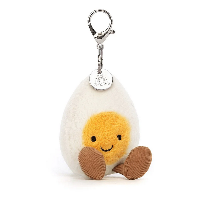 The Happy Boiled Egg Bag Charm facing forward with the egg white and yellow yolk with a smiling face. It has a silver chain, lobster claw clasp and Jellycat charm. 
