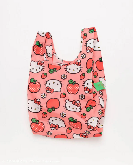 Standard Baggu bag in the Hello Kitty Apple print. Which has a peach background with Hello Kitty's face, red apples, and polka dotted apples as well as strawberries all over it. 