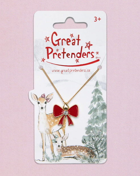The Holiday Bow Necklace on a hang card with a winter scene printed on it. 