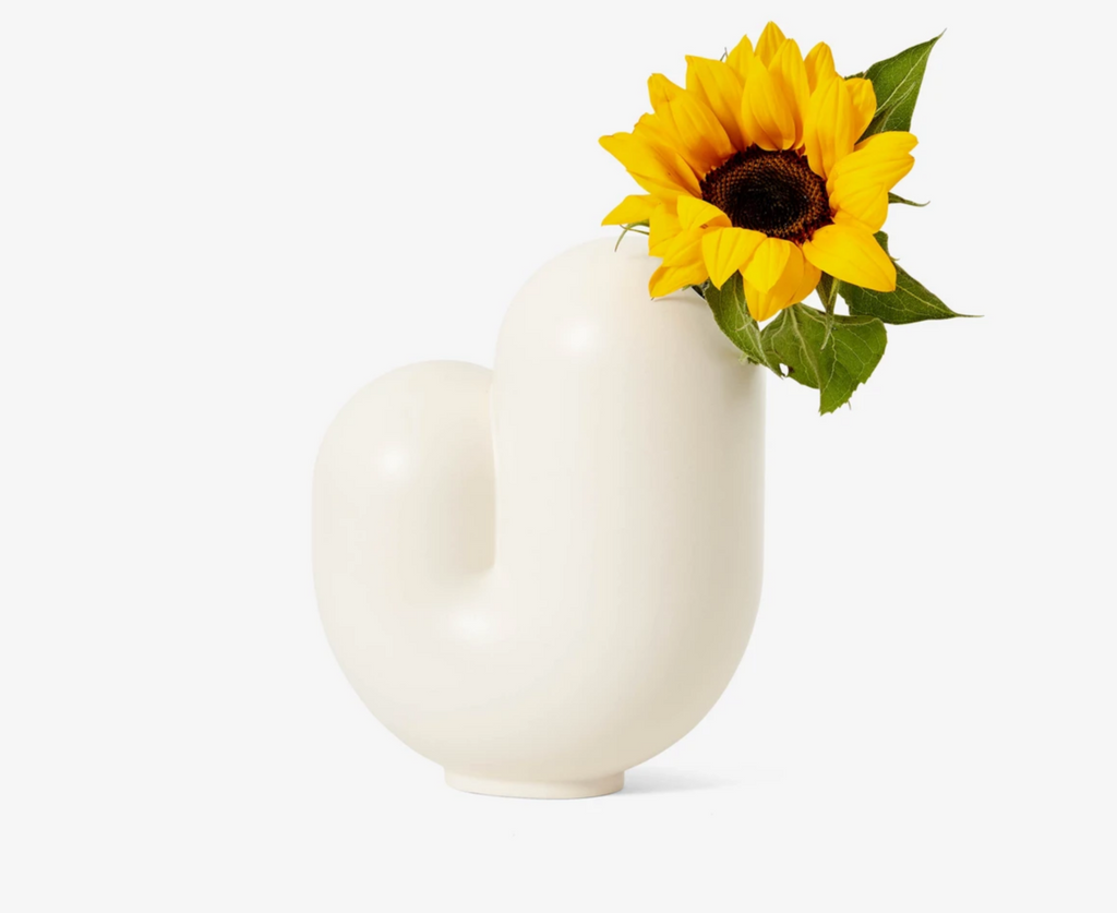 White matte ceramic Jay Kirby abstract shaped vase with a yellow sunflower.