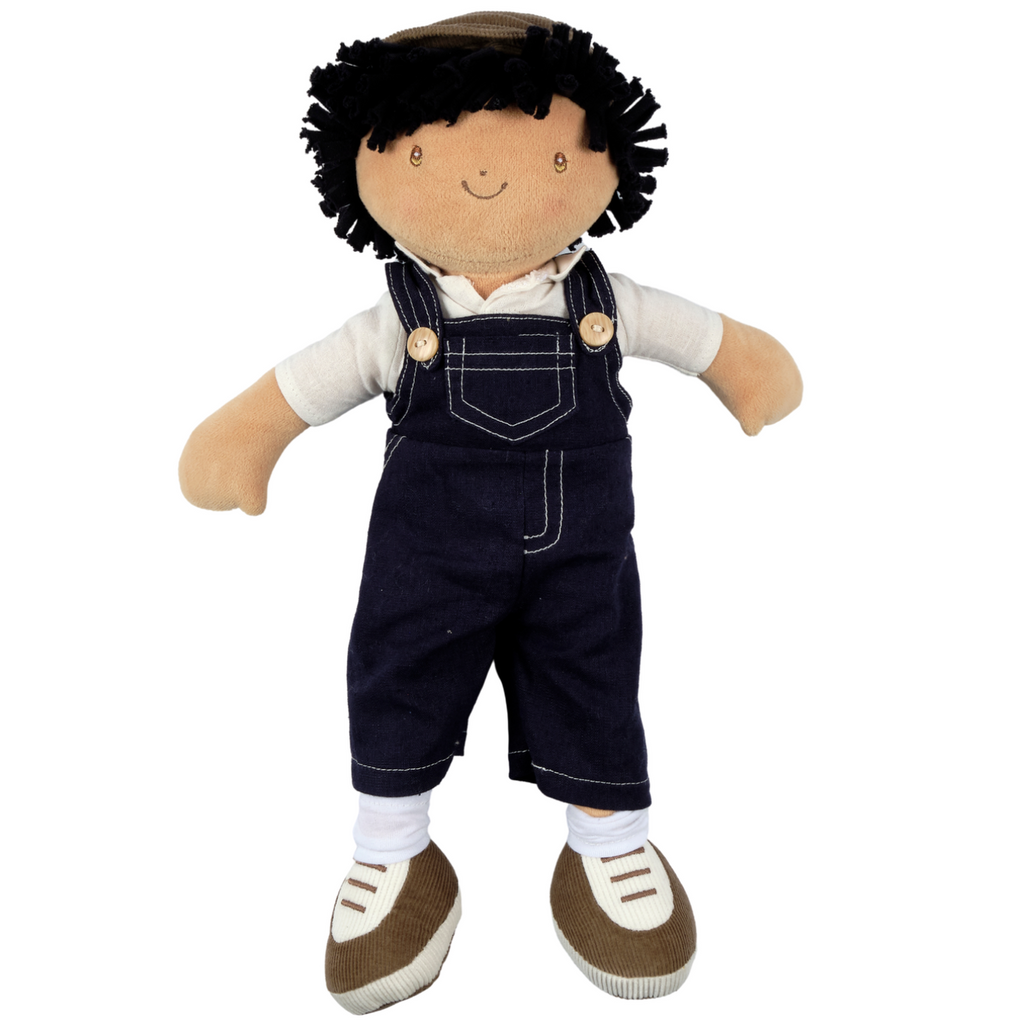 Soft boy doll with black hair. Joe is wearing a brown cap, blue overalls, a white shirt, white socks, and brown fabric shoes.