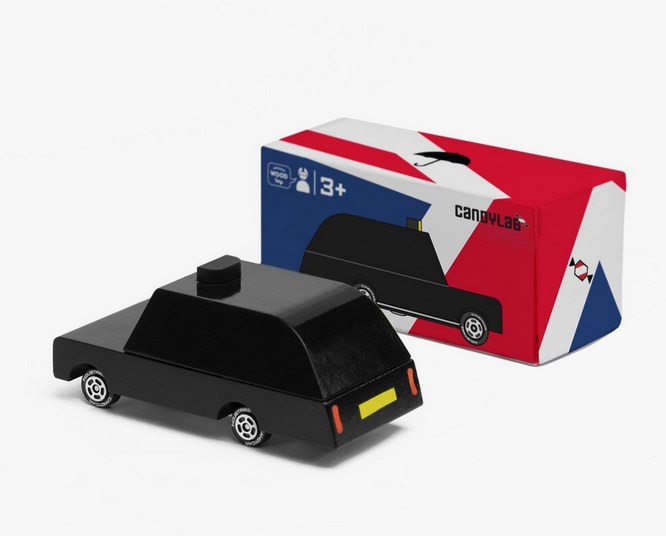Black Londaon Taxi with yellow license plate sitiing in front of it's box printed in blue, red and white the colors of the Union Jack. 