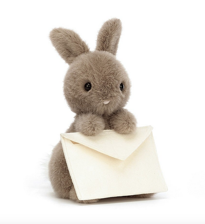 Small plush brown bunny holding a white envelope. 