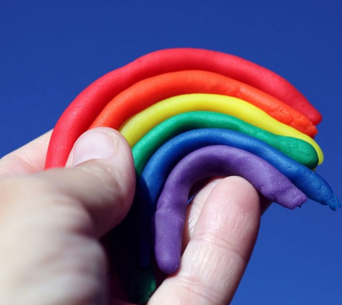 The pieces of clay included in this mini set molded into a rainbow and held in the palm of a hand.  Colors included are pink, yellow, orange, red, blue and green. 