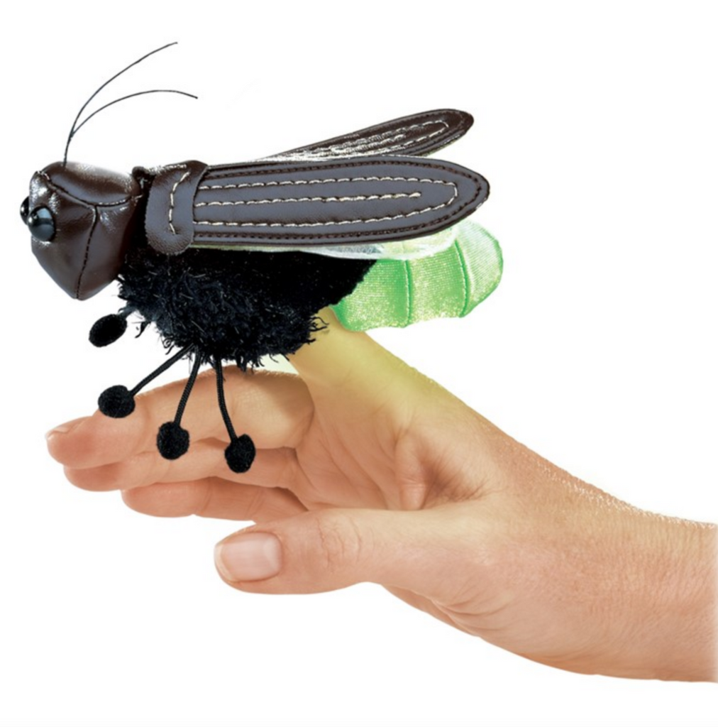 Firefly finger puppet with black body and dark brown leathery wings perched on a finger glowing. 
