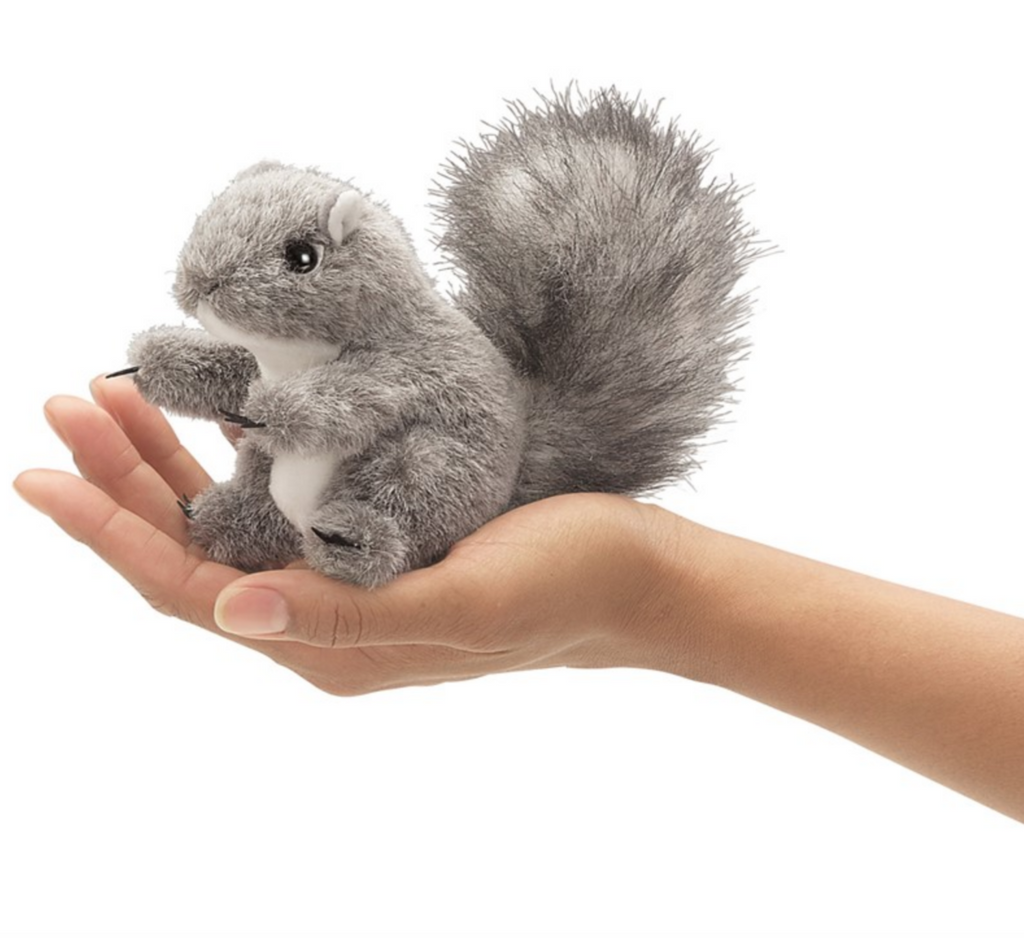 Hand holding a grey furry squirrel finger puppet.