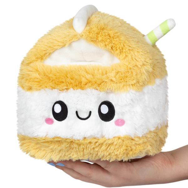 A super cute, super sweet plush mini oat milk carton.The base and top of the carton are a fuzzy light yellow and has a green and white striped straw sticking out. The center of the carton is white with Squishables signature smile. 