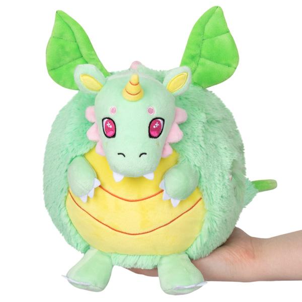 Plush dragon with mint green fur, a yellow lined belly and wide pink eyes. It's horn matches the belly and the wings are a bright green. The roundness of this dragon plushie makes  it extra huggable. 
