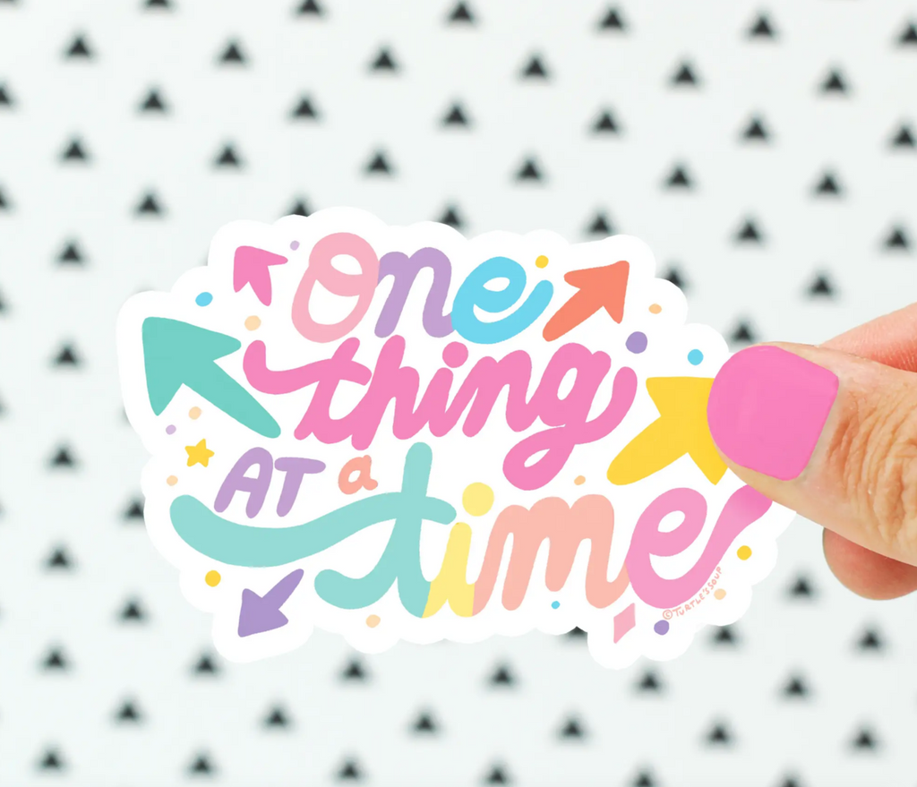 One sticker that reads "One Thing at a Time" in pastel colors.