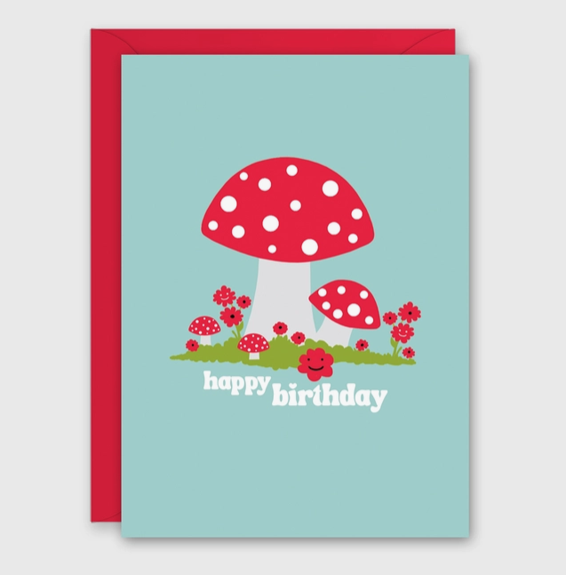 Greeting card with illustration of red capped mushrooms with white polks dots on the front. Reads "Happy Birthday"