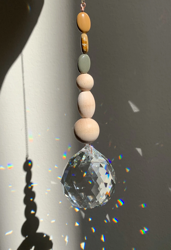 Clear prism hanging on a gold chain with 3 stones and 3 wooden beads.