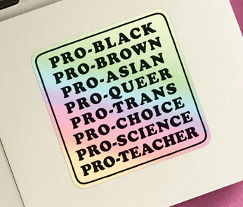 Square holographic sticker with rounded edges that reads, Pro-Black, Pro-Brown, Pro-Asian, Pro-Queer, Pro-Trans, Pro-Choice, Pro-Science, Pro-Teacher. The sticker is attached to the bottom corner of a lap top. 
