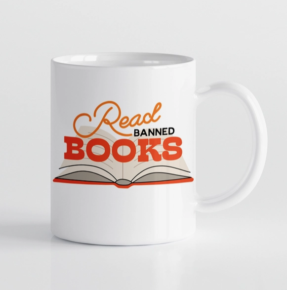 White ceramic mug with an open book that reads " Read Banned Books" 