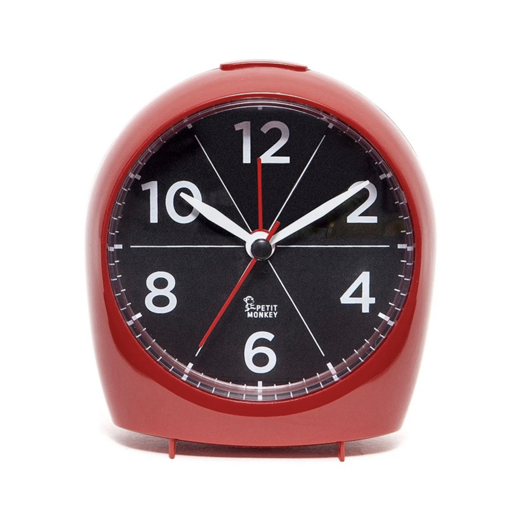 Shiny red plastic alarm clock. Clock face is round, black and has oversized white 12, 2, 4, 6, 8, and 10 numbers.