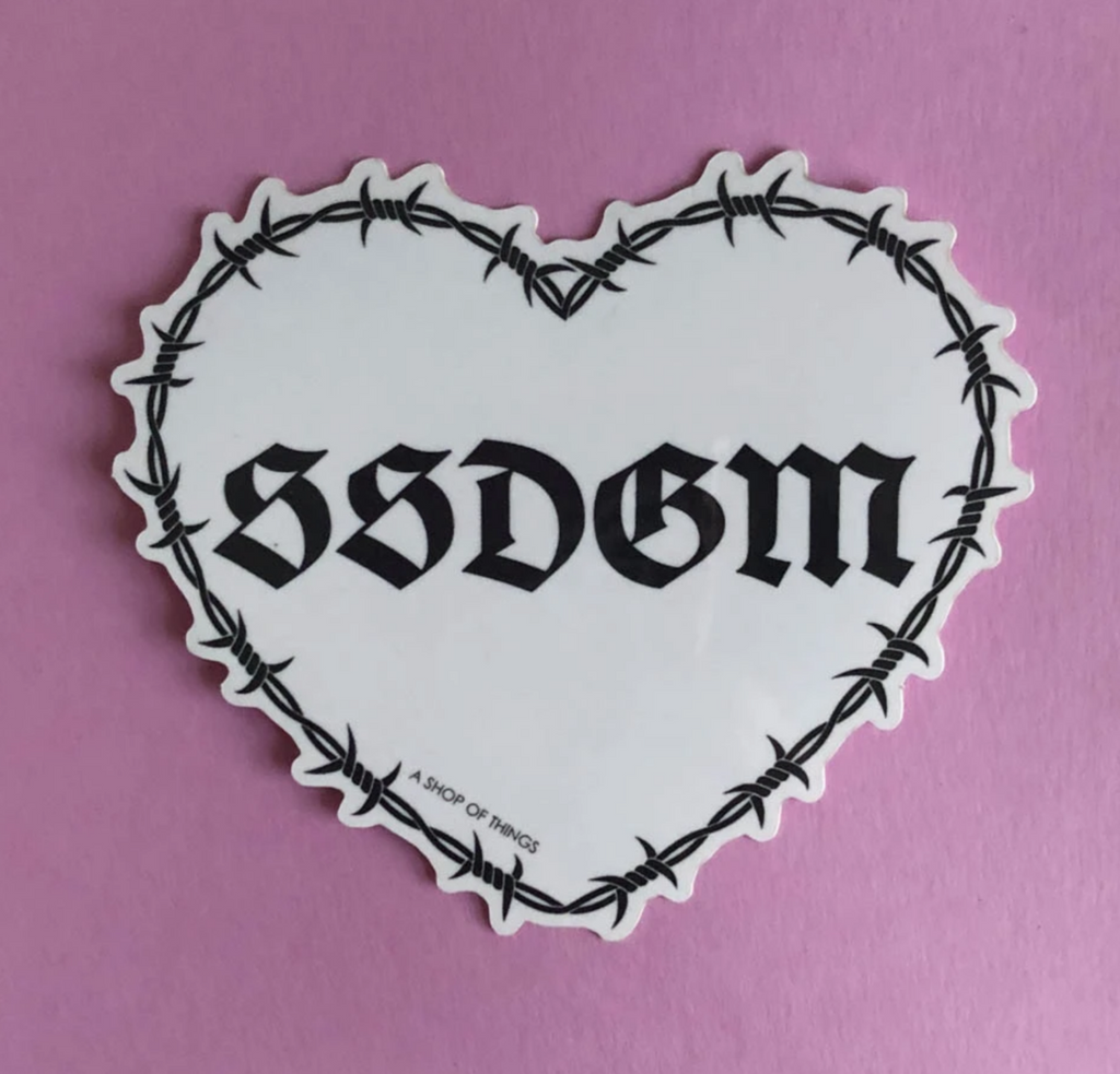 White heart sticker. Black text reads SSDGM. Black barbwire design around edges.