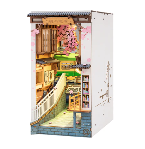 Sakura Tram Nook kit. This stunning piece is sure to capture your imagination with its Japanese architecture and cherry blossom trees. This model comes with laser-cut pieces and printed designs to give a more lifelike miniature scene. Textured material gives an illusion of flowing water, and the mirror backing extends the scene.