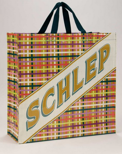 Shoulder tote in a plaid print with yellow, green, white, pink, plum, over a tan background. The word SCHLEP in a banner in gold letters running diagonally across the whole bag. 