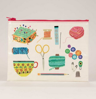 A large envelope pouch with a white background and illustrations of a pin cushion, spool of thread, buttons, a needle, a ball of yarn, scissors, thimble, marking pencil and tea cup on it. The zipper is red. 