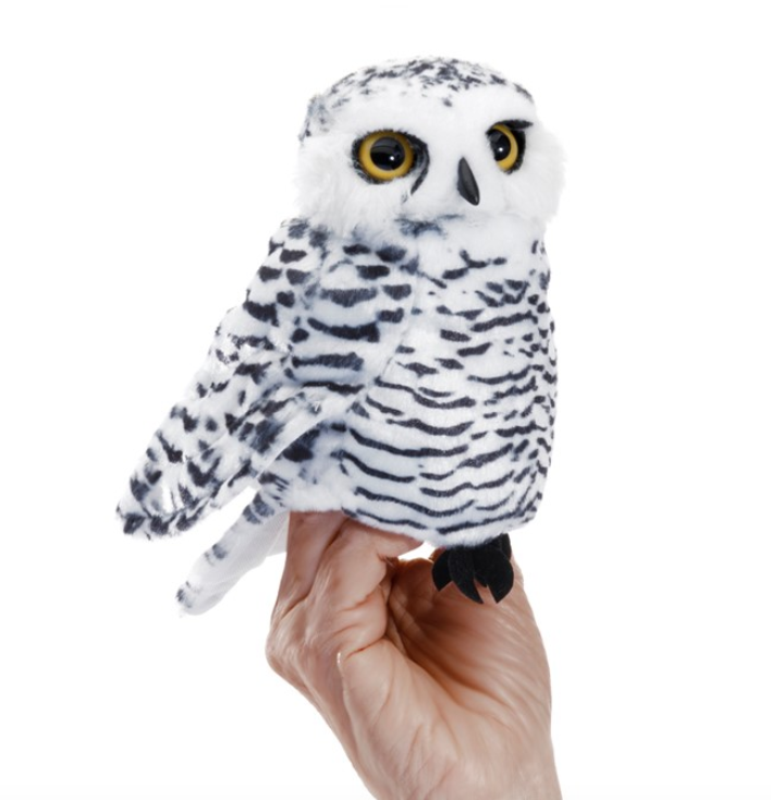 The small Snowy Owl puppet on a hand with it's white and grey fur and wide yellow eyes. 