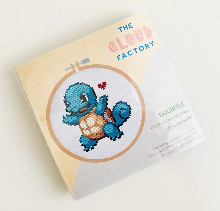 The Squirtle Love Cross Stitch kit in it's package with an illustration of the pattern of Squirtle with a small heart beside him. 