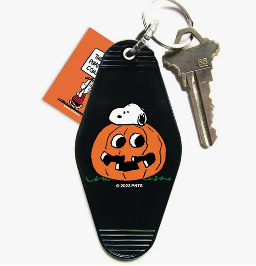 Black plastic key tag with orange pumpkin and Snoopy illustration. 