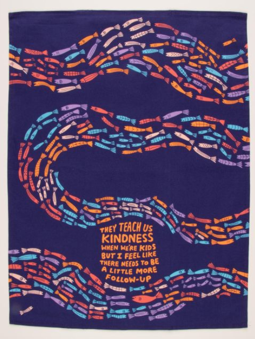 Blue dishtowel with a zig zag of rainbow fish. Text reads They teach us kindness when we're kids but I feel like there needs to be a little more follow-up.