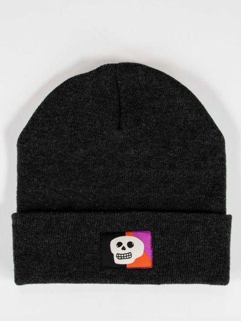 Black beanie with a white skull on a black, purple, and orange embroidered tag. 