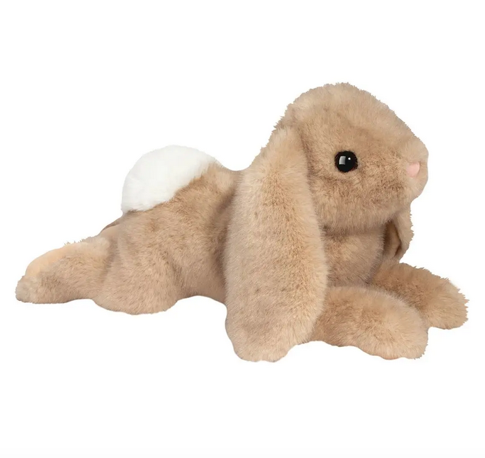 Thistle Bunny stuffed animal lying on it's tummy with light tan fur and white cottontail. It's legs are stretched out behind it and it's paws are out in front of it .