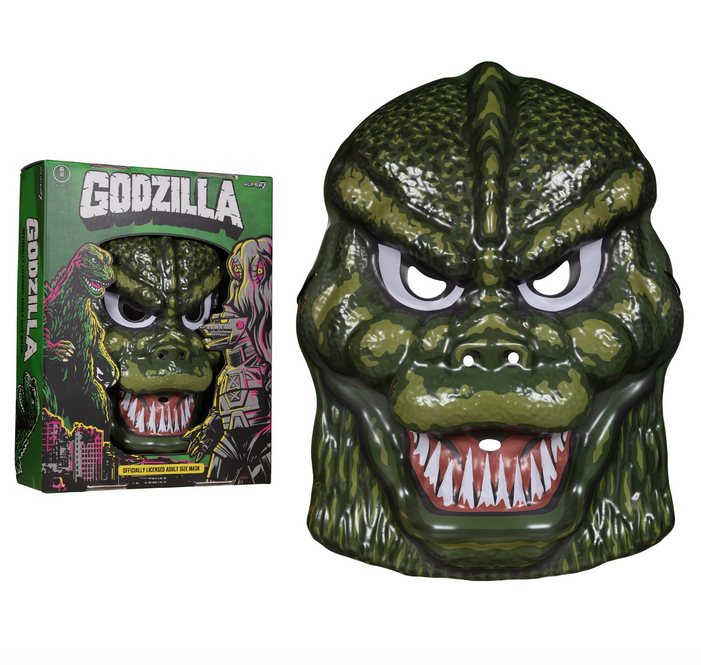 Close up of the Green Godzilla mask and the box it comes packaged in. The mask has the eye holes cut out, as well as nose and mouth holes. Godzillas menacing teeth are are on full display. Box is green with Godzilla written in white across the top and illustrations of Godzilla towering above a city, and Mechagodzilla and Hedorah illustrations. 
