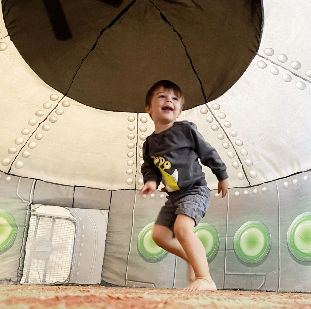 Small child playing inside inflated UFO airfort.