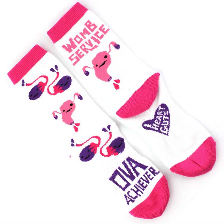 White socks with pink ring around the top and toes, with cartoon ovaries and uterus on them.  "Ova Achiever" is written on the front and "Womb Service" on the back