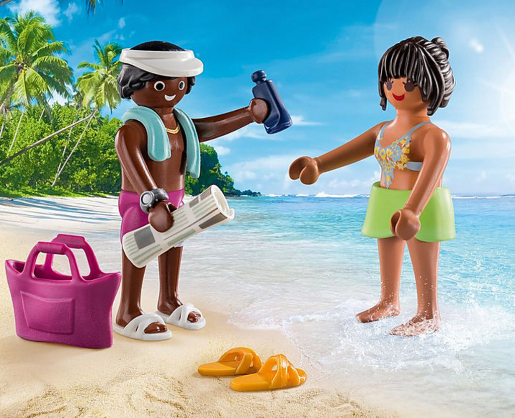 Vacation couple figures at the beach with their accessories. Man is wearing purple swin trunks, a white visor, and white sandals. Woman is weraing a bluw swimsuit and green shorts. She has orange slides. Also includes a towel, beach bag, newspaper, sunscreen bottle, and a watch.