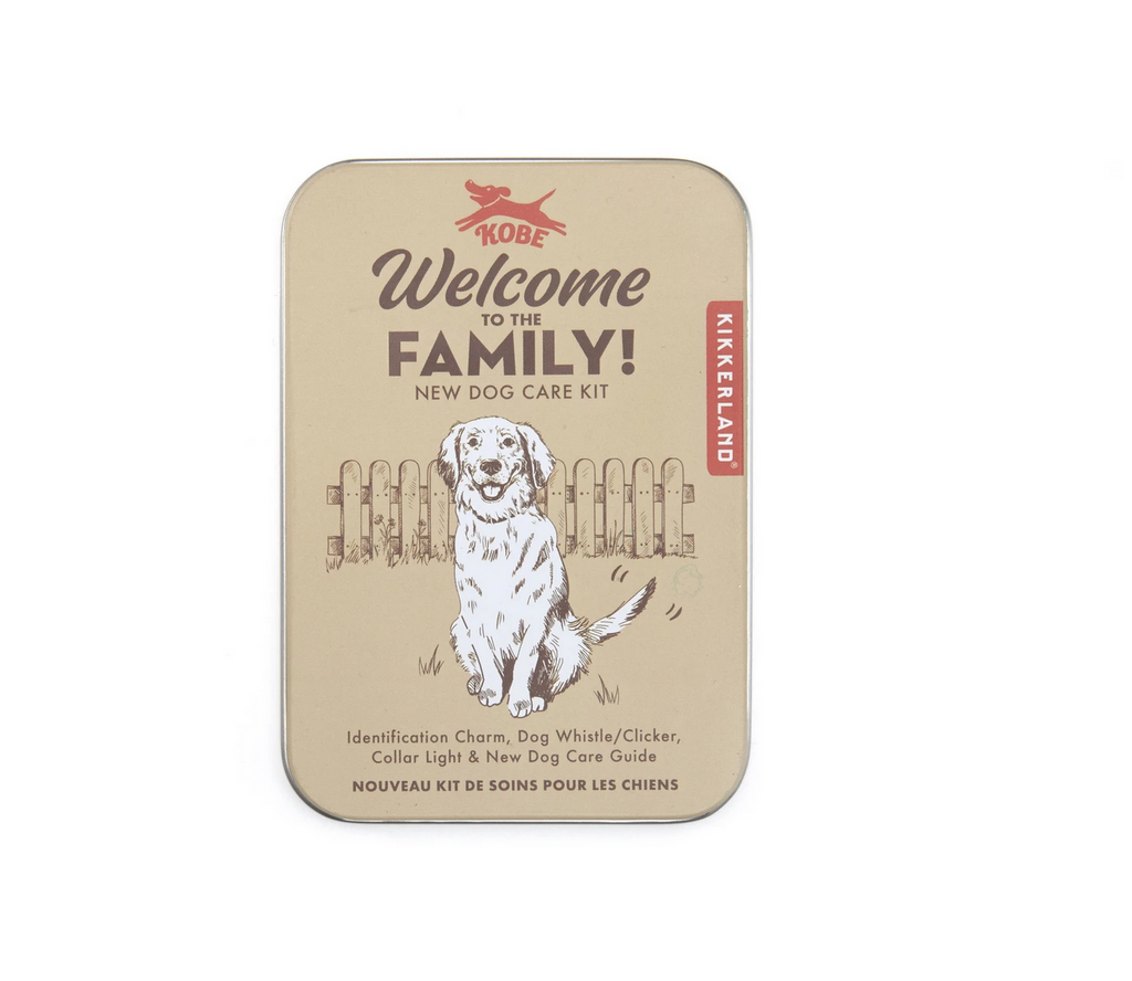 Welcome to the family new dog care kit tin. Identification charm, dog whistle/clicker, collar light & new dog care guide. Drawing of white dog sitting in grass in front of a wooden fence.